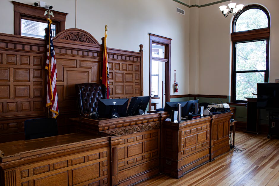 Illustration depicting a courtroom scene with a judge, a defense attorney, a prosecutor, and a defendant standing in the dock.